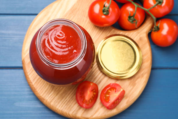 istock Organic ketchup in jar and fresh tomatoes on blue table, top view. Tomato sauce 2196836719