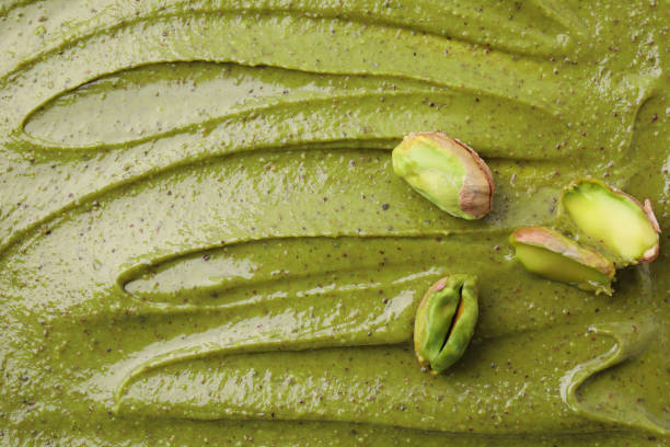 istock Fresh pistachio nuts on tasty cream, above view 2196837619