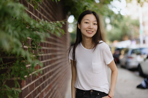 istock Smiling Woman Posing Outdoors by a Brick Wall on a Sunny Day 2196837853