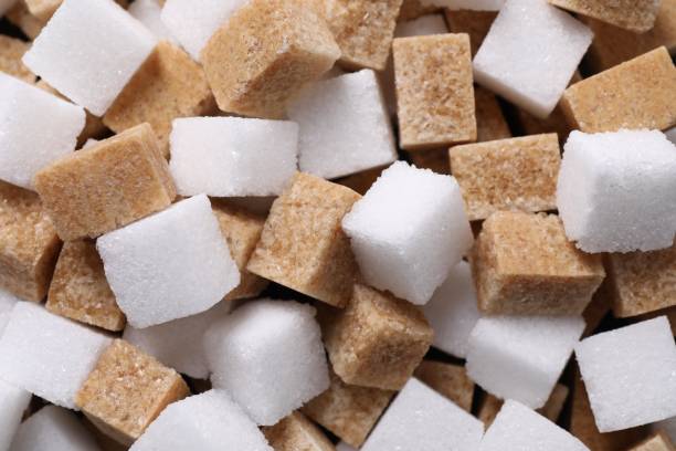 istock White and brown sugar cubes as background, top view 2196837903