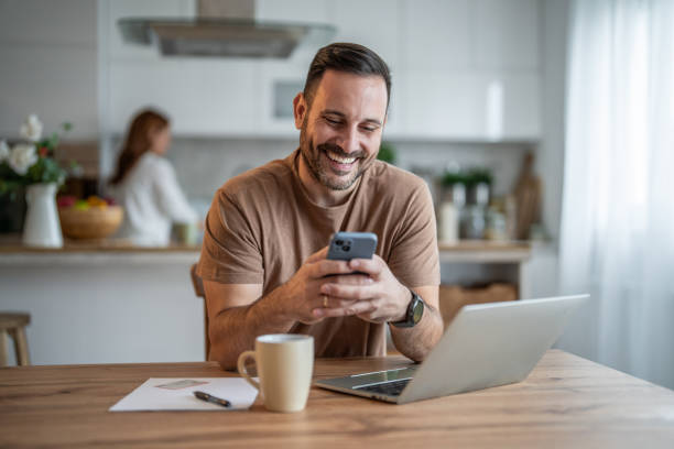 istock Focused professional man smiling at smartphone in his home office 2196838303