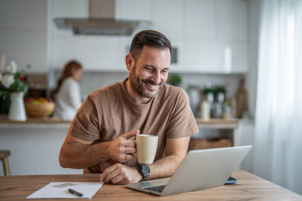 Happy man sipping coffee and working on his laptop