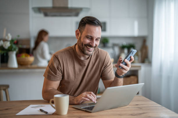 istock Busy young man managing tasks on his laptop and phone 2196838323