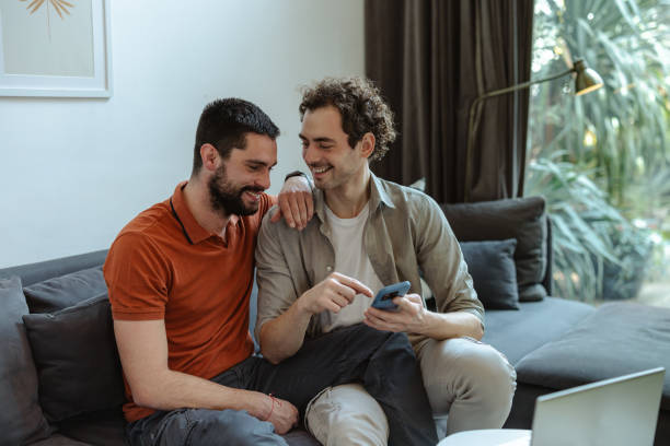 istock Gay couple enjoying a relaxing moment at home while using smartphone 2196839611