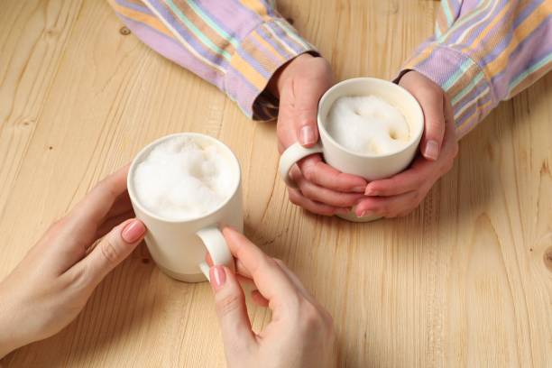 Women having coffee break at light wooden table, closeup