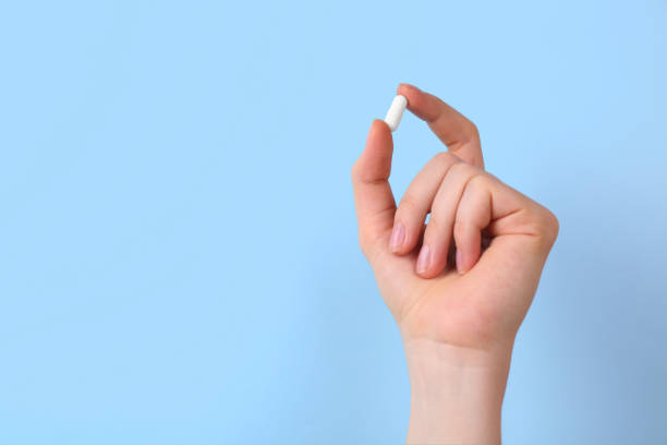 istock Woman holding vitamin capsule on light blue background, closeup. Space for text 2196844140