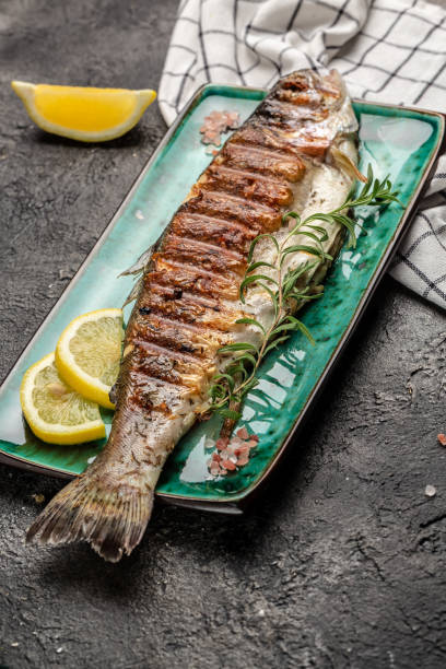 istock Baked trout fish with salt, lemon on black background. Healthy eating concept. vertical image. top view. place for text 2196844449