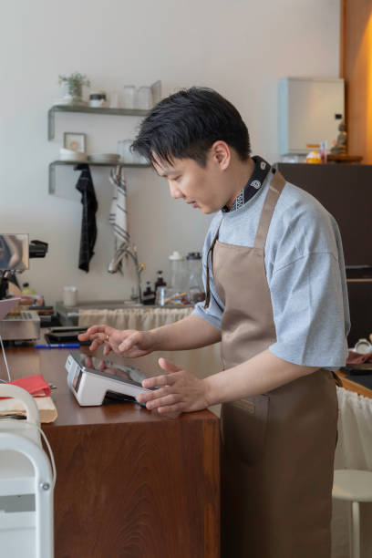 Asian man baristas to take orders from customers on touchscreen tablet. Concept coffee cafe shop.