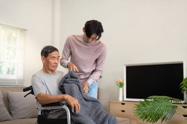 istock Son covering elderly father with a blanket in a cozy living room setting. 2196851866