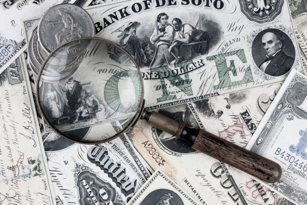 istock Retro vintage US greenback banknotes and silver certificates with silver dollar coins and magnifying glass 2196853528