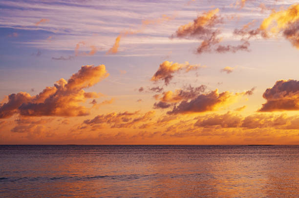 Dusk, evening sunset sky clouds over sea with colorful orange sunlight, Horizon sea sky background.