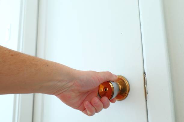 istock Male hand holding door handle on white door. 2196860885