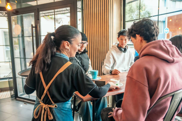 istock Friendly waitress pouring coffee for young customers, radiating warmth in sleek contemporary cafe setting with casual social interaction 2196871742