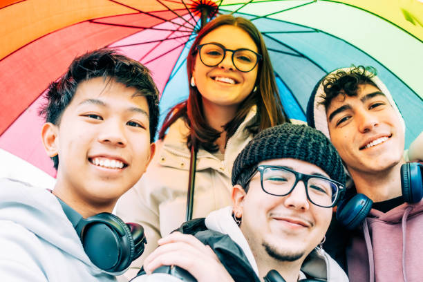 istock Diverse college students smiling, sharing colorful rainbow umbrella, expressing camaraderie and inclusivity on campus during social gathering 2196871795