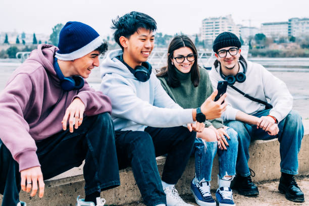 istock Multiethnic friends capturing group selfie while sitting outdoors, wearing casual attire and headphones, radiating youthful camaraderie 2196871847