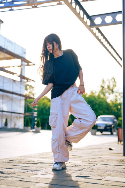 istock Young woman dancing outdoors in urban setting during golden hour with bright sunlight illuminating the surroundings 2196873852