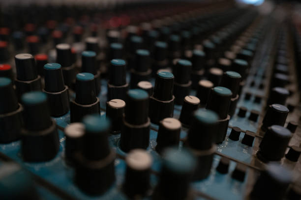 Control knobs of an audio mixing console are prominently displayed in a recording studio. Various settings are being adjusted during an active music production session.