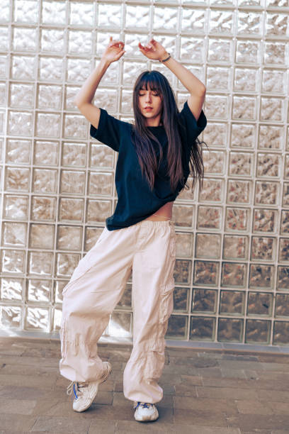 istock Dancer performing expressive movements in urban setting with glass brick background during daylight 2196874036