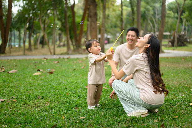 istock Little boy having playing with bubble with his parents in a lush green park 2196880749