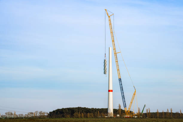 A large crane hoisting a wind turbine component, with a distant view showing the entire crane. Some copy space in the sky.
