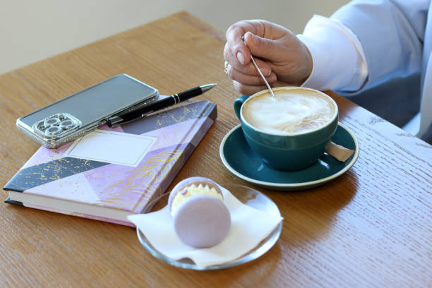istock Cafe table with coffee and donut, notebook, smartphone and sunglasses. 2196886369
