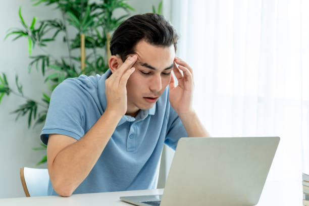 istock Depressed Asian man freelancer using laptop device working in house. Attractive male feel worried and frustrated while overworking and use notebook device communicate online in living room at home. 2196890062