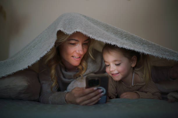 istock Mother lying on the bed with her daughter and bonding while using a cellphone 2196894170