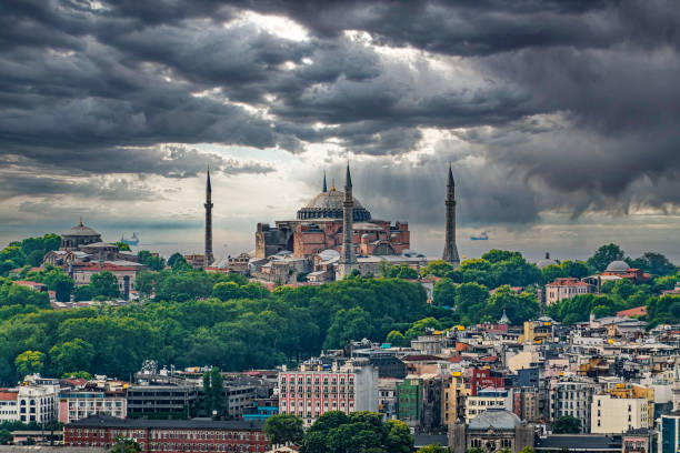 Majestic view of Hagia Sophia, an iconic architectural marvel in Istanbul, beneath moody skies, showcasing its timeless beauty amidst surrounding greenery and the bustling cityscape.