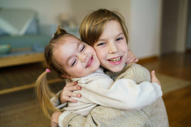 Happy brother and sister embracing at home