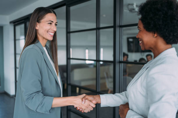 istock Business persons shaking hands in office corridor. 2196901200