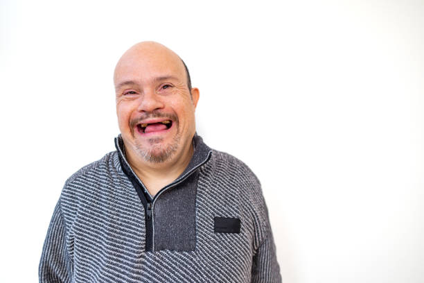 Cheerful man with Down syndrome posing in front of a white wall