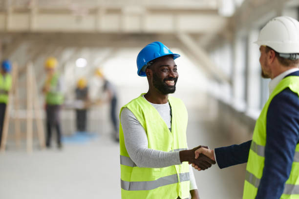 istock Happy black worker shaking hands with an architect at construction site. 2196904688