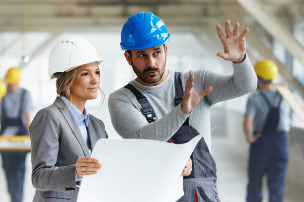 istock Female architect and manual worker making plans at construction site. 2196904924