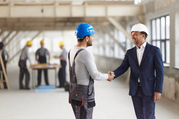 istock Happy male architect and his worker shaking hands at construction site. 2196904962