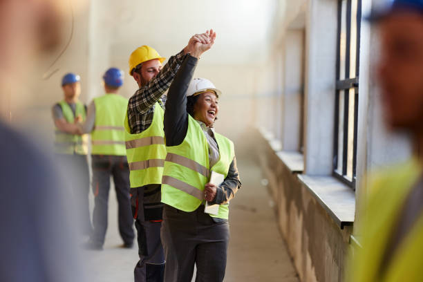 istock Playful female interior designer dancing with manual worker at construction site. 2196905315