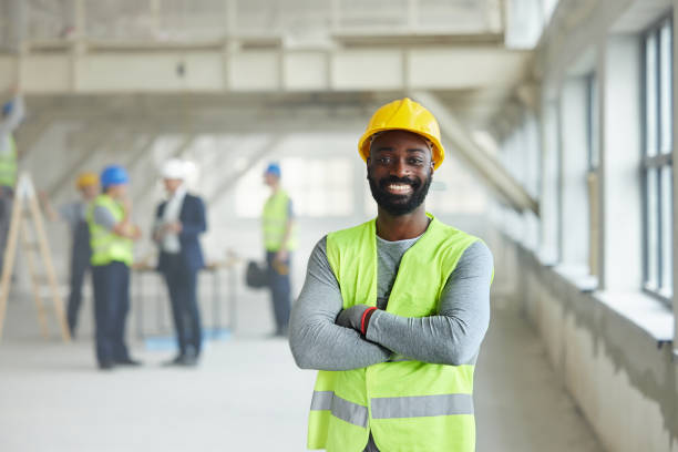 istock Happy black worker with crossed arms at construction site. 2196905343