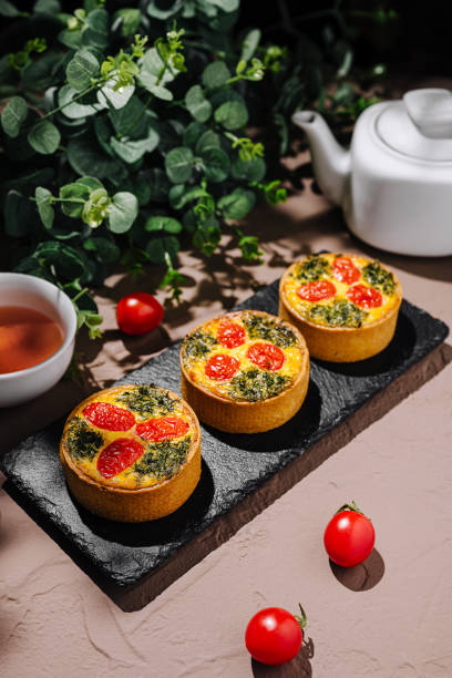 istock Colorful savory tarts with spinach and cherry tomatoes served on a slate plate with tea 2196905652