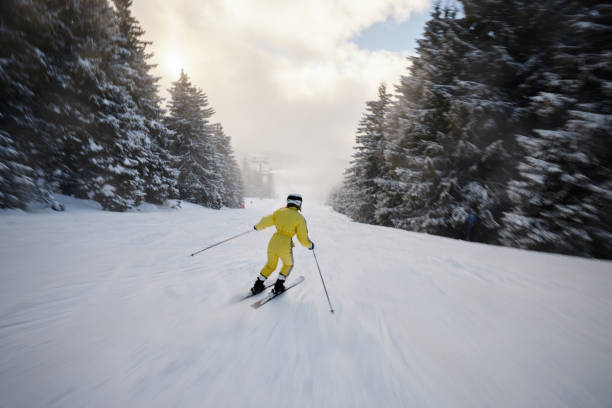 Rear view of a female skier moving down the slope during winter day on a mountain. Copy space.