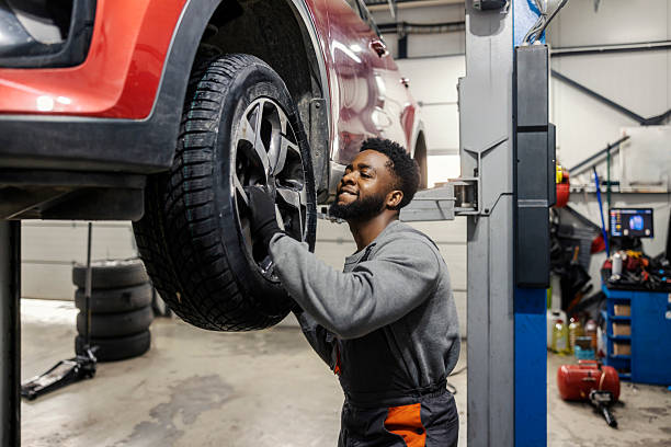 istock Hardworking multicultural car mechanic standing at car workshop and changing tires. 2196907556