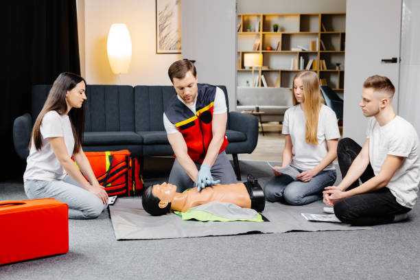 istock Young man instructor helping to make first aid heart compressions with dummy during the group training indoors 2196909512