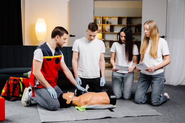 istock Young man instructor helping to make first aid heart compressions with dummy during the group training indoors 2196909521