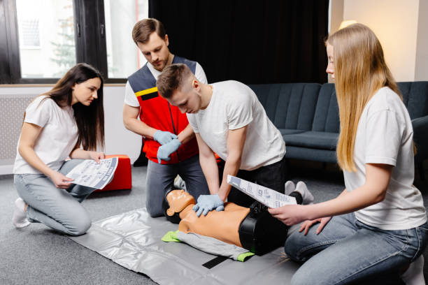 istock Young man instructor helping to make first aid heart compressions with dummy during the group training indoors 2196909526