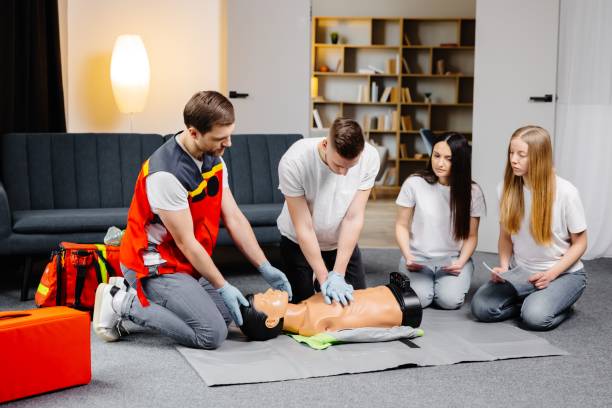 istock Young man instructor helping to make first aid heart compressions with dummy during the group training indoors 2196909531