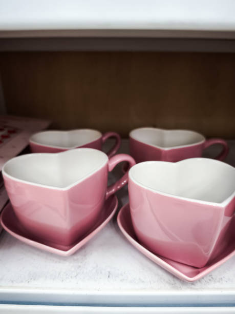 Pink heart shaped teacups and saucers are neatly arranged on a shelf, ready for a romantic occasion or everyday use Valentines Day