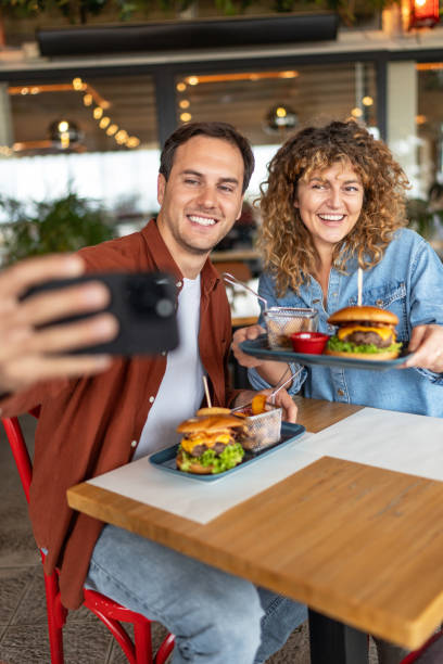 istock Happy couple taking selfie with smart mobile phone at burger pub restaurant 2196913719