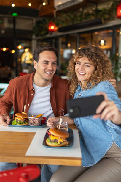 istock Happy couple taking selfie with smart mobile phone at burger pub restaurant 2196913956