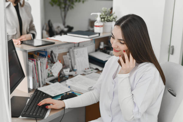 istock Nurse Working On Computer And Talking On The Phone Simultaneously At Medical Reception 2196915620