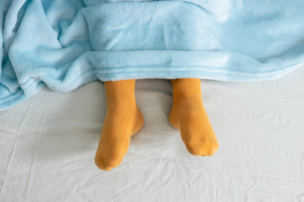 istock Child sleeping peacefully in bed wearing colorful socks and covered by soft blanket 2196916413