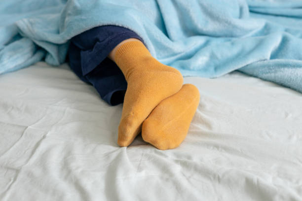 istock Child sleeping peacefully in bed wearing yellow socks and covered by blue blanket 2196916526