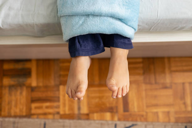 istock Child wrapped in blanket hanging feet over bed 2196916672